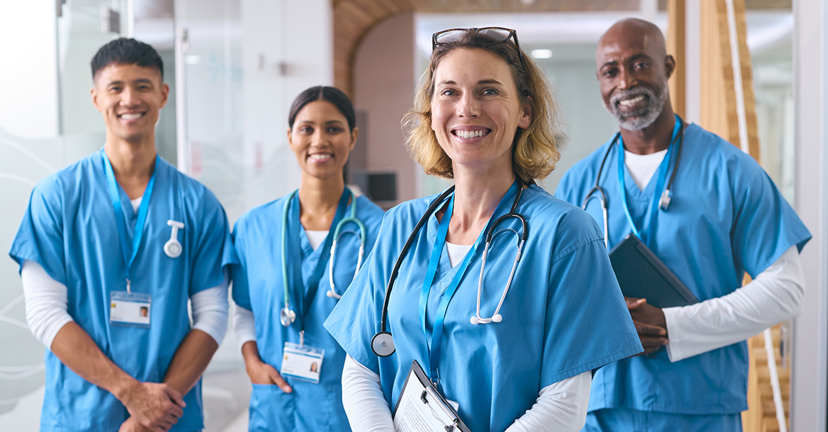 Smiling Multi Cultural Medical Team Wearing Scrubs In Modern Hospital